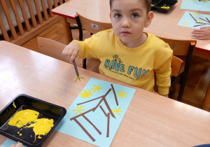 Chłopiec maluje żółtą farbą.