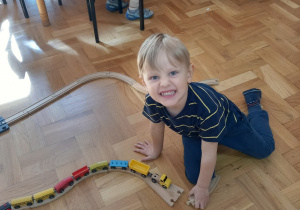 Chłopiec bawi się drewnianą kolejką.