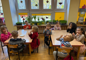 Dzieci wykonują ćwiczenia logopedyczne z użyciem chrupek kukurydzianych