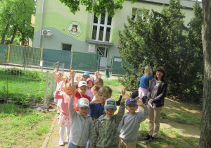 Dzieci z paniami idą sprzątać śmieci w pobiżu przedszkola.