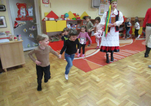 Dzieci trzymają się za ręce i podskakują.