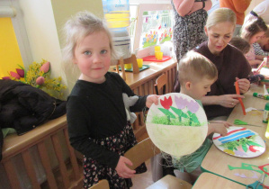 Dziewczynka pokazuje pracę plastyczną: tulipany w papierowym koszyku