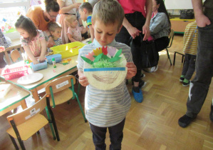 Chłopiec pokazuje pracę plastyczną: tulipany w papierowym koszyku.