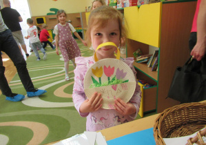 Dziewczynka pokazuje pracę plastyczną: tulipany w papierowym koszyku
