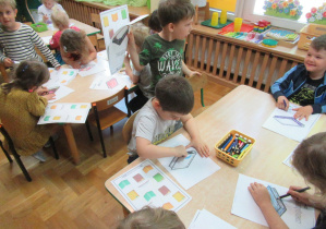 Przedszkolaki kolorują obrazki.