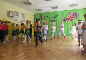 Dzieci maszeruja i grają na tamburynach.