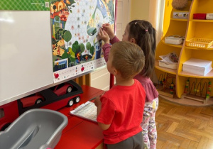 Dzieci przyklejają naklejki na plakat