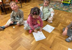 Dzieci przyklejają na kartkę obrazki przedstawiające poszczególne etapy cyklu rozwoju motyla