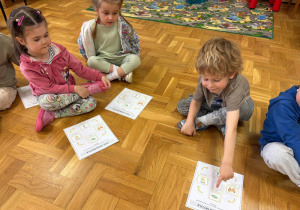 Dzieci przyklejają na kartkę obrazki przedstawiające poszczególne etapy cyklu rozwoju motyla