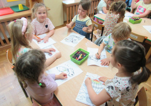 Przedszkolaki kolorują obrazki.