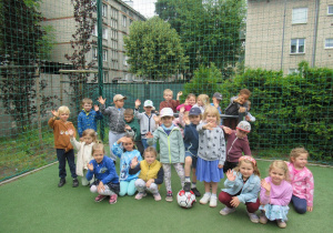 Dzieci pozują do zdjęcia na boisku przedszkolnym.