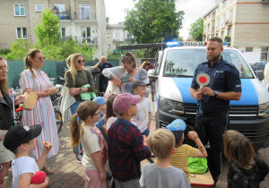 Policjant opowiada dzieciom o pracy podczas pikniku.