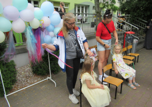 Mamy robią dziewczynkom warkoczyki.