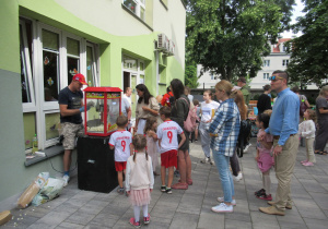 Dzieci i rodzice stoją w kolejce po popcorn.