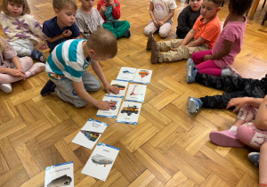 Chłopiec układa obrazki przedstawiające pojazdy