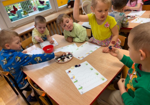Dzieci układają guziki na szlaczkach