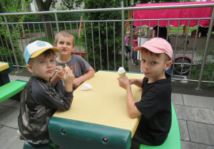 Przedszkolaki siedzą i jedzą lody.
