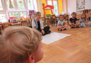 Pani ubrana w biały fartuch trzyma w ręku pacynkę.