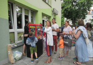 Rodzice i dzieci stoją na przedszkolnym tarasie.