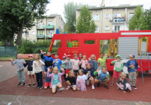 Dzieci pozują do zdjęcia w ogródku przedszkolnym.