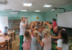 Dzieci łapią bańki mydlane, które robi pani podczas zajęć Roar Dance.