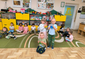 Dzieci trzymają słoiki z zabarwioną wodą