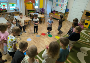 Dzieci stoją wokół palety malarskiej ułożonej z kół origami