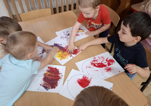 Przedszkolaki wykonują pracę plastyczną ,,Parasolki"