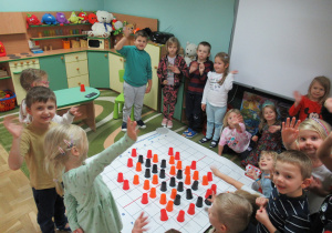 Dzieci stoją wokół maty do kodowania.