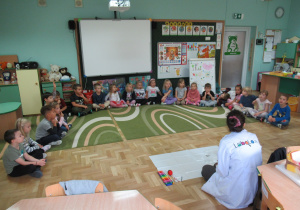 Dzieci siedzą na dywanie podczas warsztatów Labo.