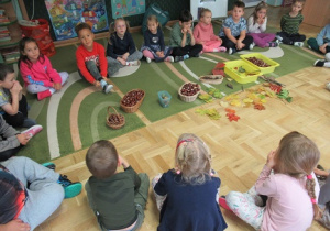 Dzieci siedzą w kole, przed nimi dary jesieni.