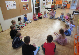 Dzieci siedzą w kole, trzymają w rękach instrumenty podczas rytmiki.