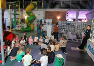 Dzieci siedzą w kole w sali zabaw.