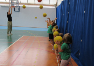 Dzieci ćwiczą rzuty piłką.