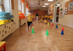 Dzieci pokonują tor przeszkód podczas zajęć ogólnorozwojowych z elementami teakwondo.