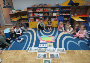 Dzieci siedzą na dywanie podczas zajęć, przed nimi mapa Polski i ilustracje dotyczące Fryderyka Chopina.