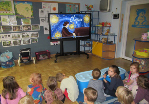 Dzieci oglądają film edukacyjny o Fryderyku Chopinie.
