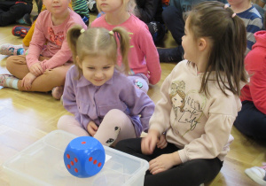 Dzieci patrzą na kostkę leżącą na pudełku - zajęcia o orientacji przestrzennej.