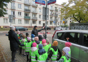 Pani pokazuje dzieciom przejście dla pieszych.