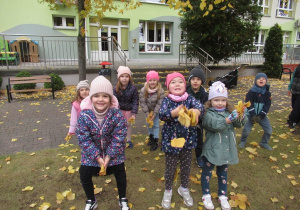 Dzieci podrzucają liście.