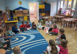 Dzieci z pania siedzą w kole podczas zajęć Roar Dance.