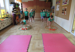 Dzieci stoją w dwóch rzędach podczas zajęć gimnastycznych.