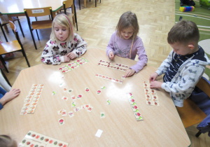 Dzieci przy stoliku układają rytmy z obrazków.