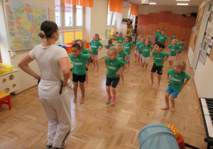 Dzieci stoją przed panią w rozsypce podczas zajęć teakwondo.