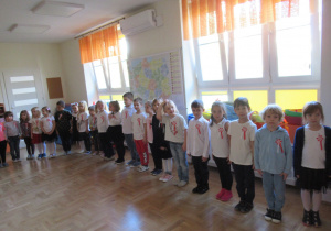 Dzieci stoją na baczność podczas śpiewania hymnu.