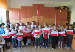 Dzieci pozują do zdjęcia trzymając w rękach biało - czerwone flagi.