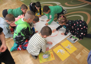 Dzieci tworzą plakat z Sercem życzliwości, rysują na kartonie leżącym na podłodze.