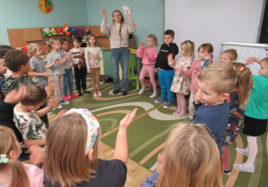 Dzieci stoją w kole podczas zajęć z języka angielskiego.