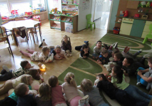 Dzieci leżą na dywanie ze swoimi misiami.