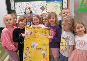 Dzieci pozują do zdjęcia z plakatem wykonanym podczas zajęć.